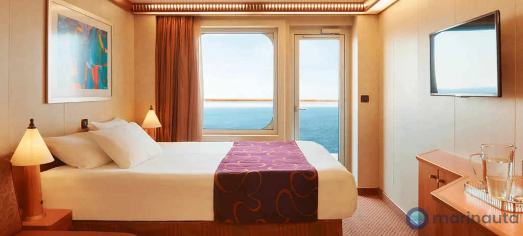 camarote con balcón visto desde la entrada, con la cama hecha y la puerta de la terraza al fondo
