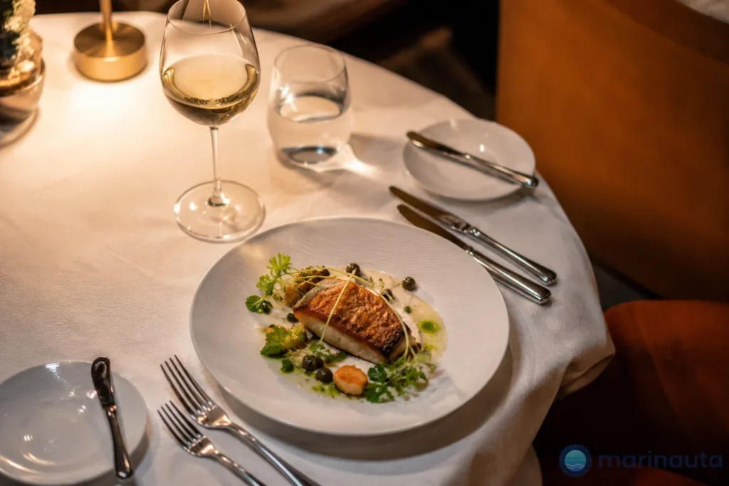 mesa puesta con un plato emplatado en un restaurante de especialidad a bordo