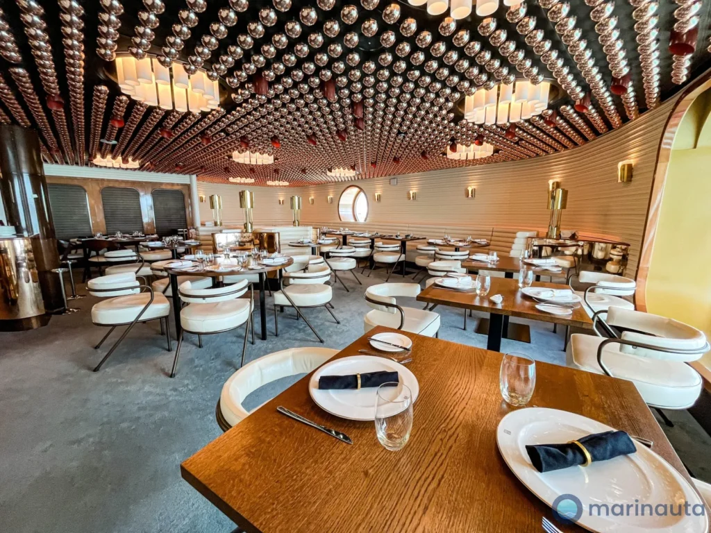 restaurante de diseño a bordo de un crucero, con mesas puestas y luz cálida